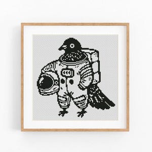 May include: A framed, pixelated black and white illustration of a bird wearing an astronaut suit and holding a helmet. The artwork is displayed in a wooden frame, perfect for home decor. The bird's head is visible above the astronaut suit.