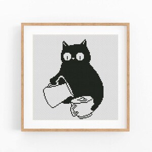 Könnte beinhalten: Ein gerahmtes Kreuzstichmuster mit einer schwarzen Katze mit großen weißen Augen, die eine weiße Gießkanne neben einer kleinen weißen Topfpflanze hält. Das Design ist im Pixel-Stil auf einem weißen Rasterhintergrund in einem hellen Holzrahmen dargestellt.