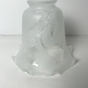 May include: A frosted glass lampshade with a scalloped edge and an etched floral design.