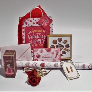 May include: Miniature Valentine's Day gift set featuring a red shopping bag with heart patterns, a box of chocolates, a perfume bottle, a card, and wrapping paper. The set includes a red rose and a pair of earrings. The bag has the text "Happy Valentine's Day".