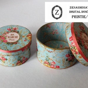 Puede incluir: Dos cajas redondas en miniatura con tapas. Las cajas son de color azul claro con un estampado floral y ribete de cinta roja. Una caja está abierta, revelando un interior dorado. Las tapas presentan una etiqueta que dice "BON MARCHE Paris". También se ve el texto "ZENASMINIATURES DIGITAL DOWNLOAD PRINTIE/PDF".