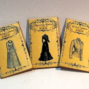Op de afbeelding: Drie vintage-stijl papieren patronen voor kleding, elk met een ander ontwerp. De patronen zijn gelabeld "Walking Costume", "Mourning Dress" en "Gored Jacket".