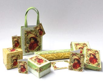 May include: A collection of decorative gift boxes, a tote bag, and cards. Each item features a vintage illustration of a child in a red coat and hat. The boxes and bag have green and yellow accents, and the overall theme is festive.