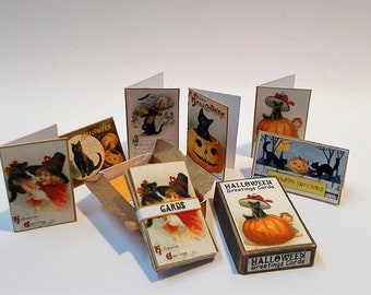 Puede incluir: Una colección de tarjetas de felicitación de Halloween de estilo vintage y una caja de tarjetas. Las tarjetas presentan ilustraciones de gatos negros, calabazas y niños con disfraces de Halloween. La caja está etiquetada como "Halloween Greetings Cards."