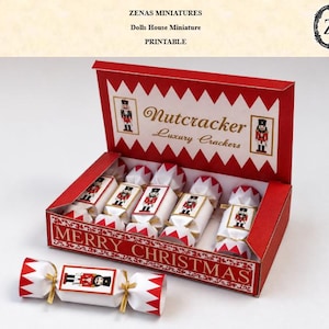 以下が含まれることがあります： くるみ割り人形のグラフィックが描かれたミニチュアのクリスマス・クラッカーが入った赤と白の厚紙製ボックス。蓋には「Nutcracker Luxury Crackers」、前面には「MERRY CHRISTMAS」の文字。箱の外にクラッカーが1つ置かれています。