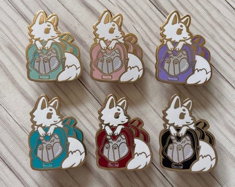 May include: Six enamel pins featuring a white fox with a backpack. The backpacks are different colors: teal, pink, purple, blue, red, and black. Each pin has the word "Farvilla" on the bottom.