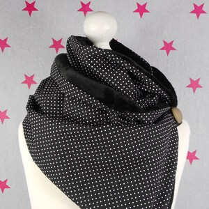 Könnte beinhalten: Schwarz-weißer Polka-Dot-Infinity-Schal mit schwarzem Fleece-Futter. Der Schal hat einen braunen Knopf an der Seite.