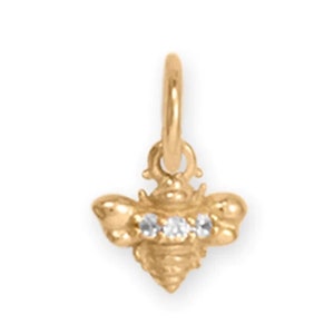 May include: Gold bee charm with three clear cubic zirconia stones.