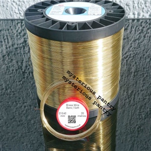 May include: A spool of gold-coloured brass wire, 0.60 mm thick, with a label that reads "Brass Wire Bare / Soft 20 metres".