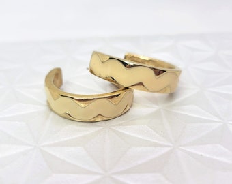 May include: A pair of gold hoop earrings with a wavy, textured design.