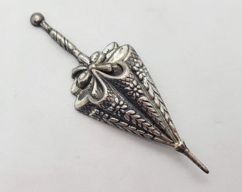 Peut inclure: Un pendentif en argent, orné, en forme de parapluie, avec une longue tige fine et pointue.