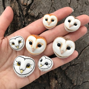 May include: A collection of seven hand-painted ceramic owl figurines. The owls are all different sizes and have realistic features, including eyes, beaks, and feathers. Some of the owls are white with black markings, while others are brown with orange markings.