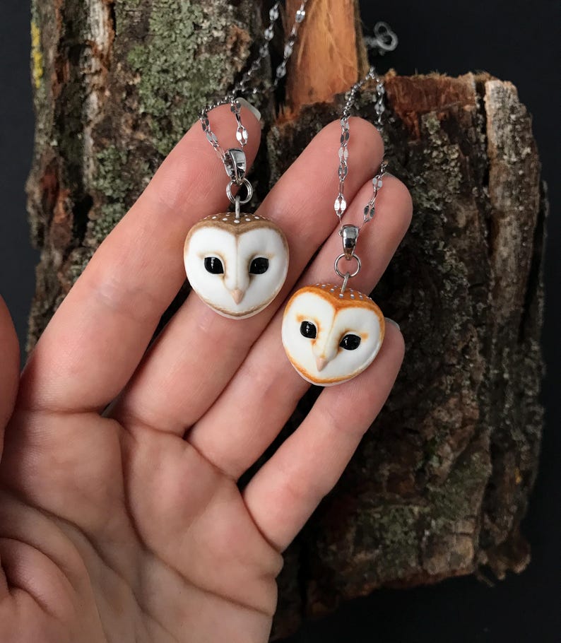 May include: Two silver chain necklaces with owl pendant charms. The owls are made of white porcelain with brown and orange accents. One owl has black eyes and the other has brown eyes.