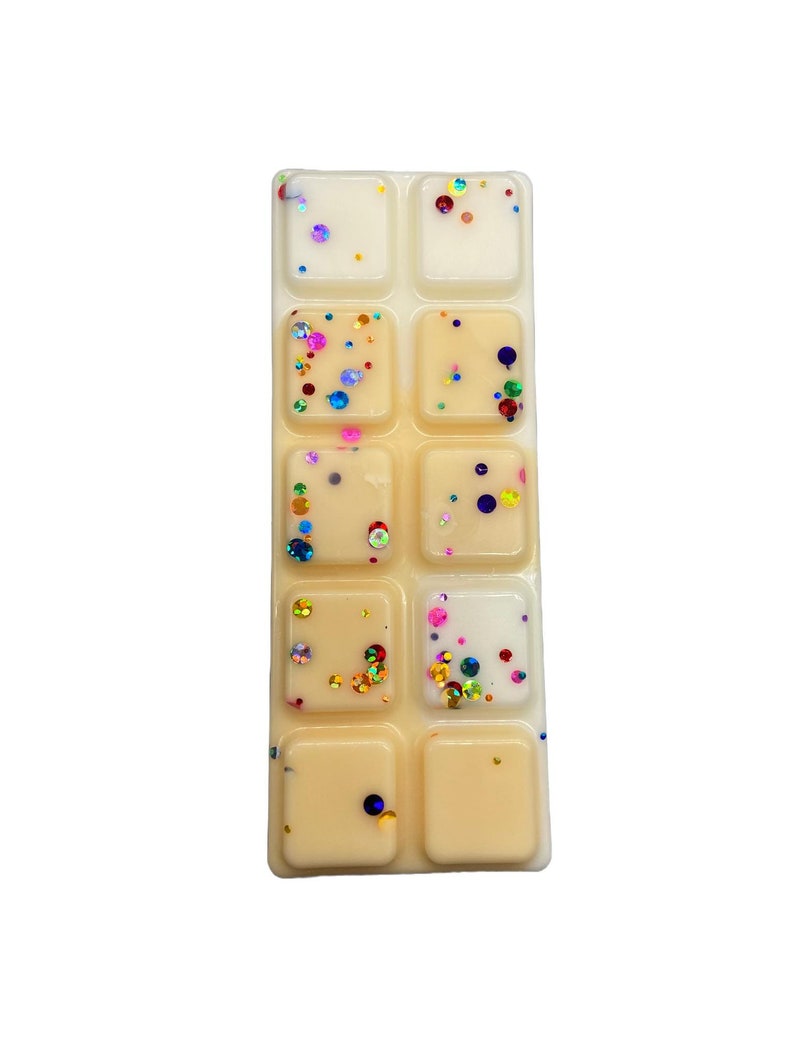 May include: A wax melt set with eight individual squares. The wax melts are a light yellow color and have colorful glitter embedded in them.