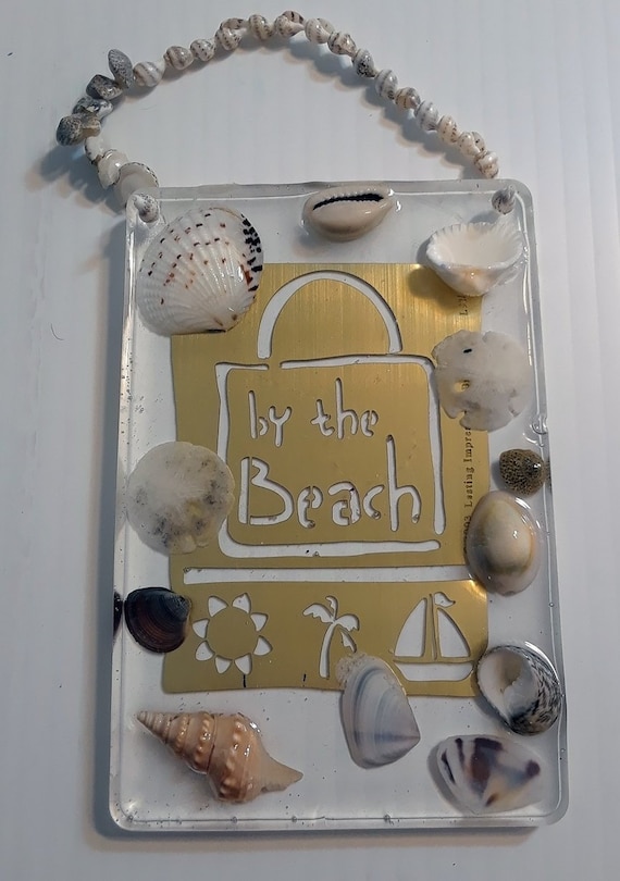 Hanging clear acrylic with "by the beach" brass sign and shells