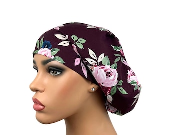 May include: A burgundy surgical scrub cap with a floral pattern. The cap features pink roses, green leaves, and white accents. The cap is designed to cover the head and hair, commonly used in medical settings.