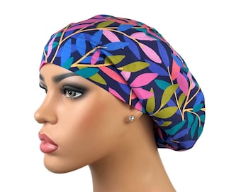 May include: A colorful surgical scrub cap featuring a botanical leaf pattern in shades of blue, pink, green, and gold on a navy blue background. The cap is designed to cover the hair and is likely used in a medical or surgical setting.