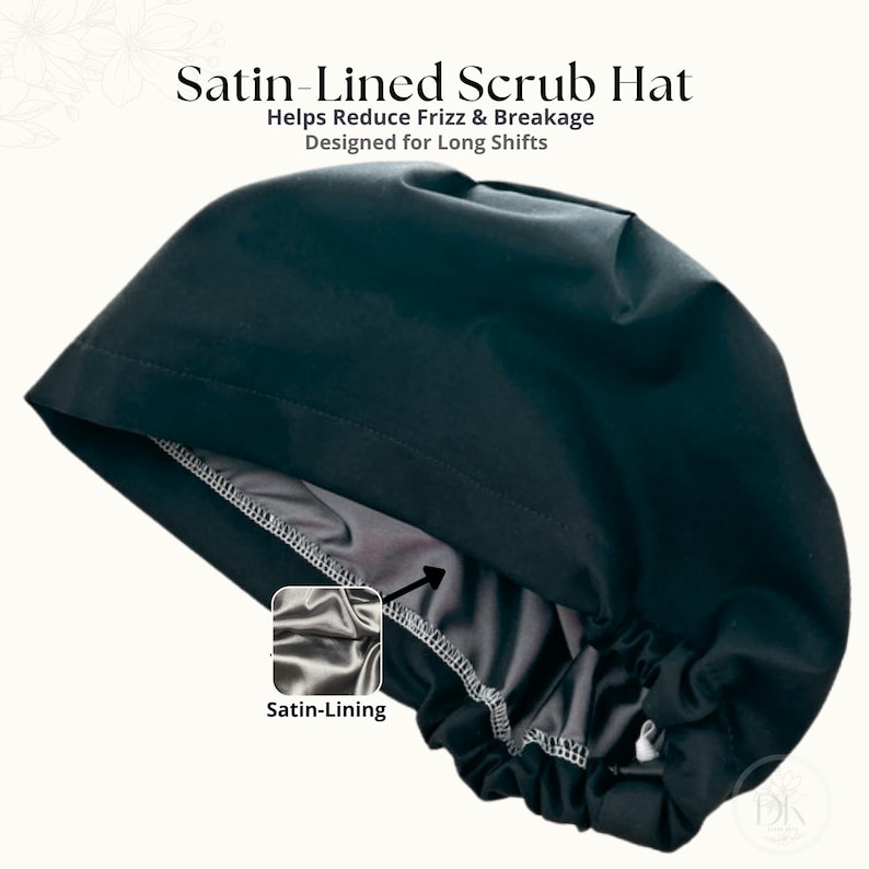 Op de afbeelding: Een zwarte operatiemuts met een grijze satijnen voering, voorzien van de tekst Satin-Lined Scrub Hat, Helps Reduce Frizz & Breakage, Designed for Long Shifts en Satin-Lining. De muts heeft een geplooide achterkant met een verstelbare sluiting.