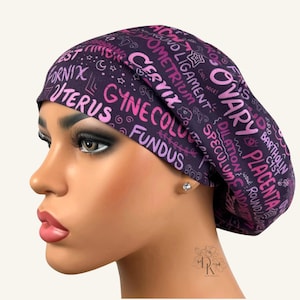 May include: A dark purple scrub cap featuring a repeating pattern of pink and light purple medical terminology including words like Uterus, Cervix, Ovary, Placenta, Fundus, Fornix, and Bartholin Cyst, along with small star and swirl icons.