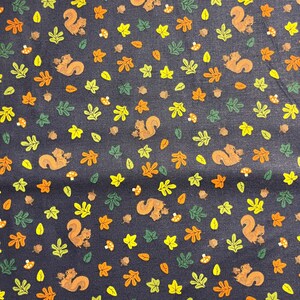 May include: A dark blue fabric with a repeating pattern of squirrels, leaves, and acorns. The squirrels are brown and have bushy tails. The leaves are green, yellow, and orange. The acorns are brown.