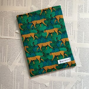 Può includere: Una pochette in tessuto verde e oro con un motivo ripetitivo di leopardi e foglie tropicali. La pochette ha un'etichetta bianca con il testo "Always September".