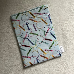 May include: A light blue fabric with a colorful crayon pattern. The crayons are arranged in a geometric design with circles, stars, and hearts. The fabric has a white border and the text "Crayola" is printed in the bottom right corner.