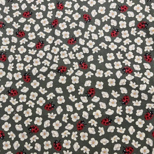 May include: A green fabric with a repeating pattern of white flowers and red ladybugs.