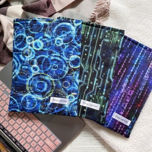 May include: Three different fabric book covers with a blue, green, and purple colour scheme. The covers feature abstract designs with geometric shapes and patterns. The text "Always September" is printed on each cover.