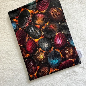 May include: A black fabric pouch with a colorful dragon egg pattern. The pouch has a white tag with the text "Sewn with Love" on it.