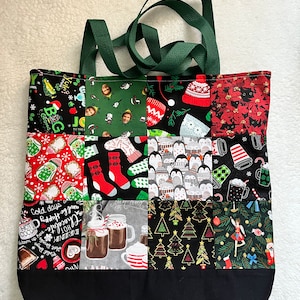 Peut inclure: Un sac fourre-tout en toile noire avec des anses vertes. Le sac est décoré d'un patchwork de carrés de tissu sur le thème de Noël représentant des pingouins, des sapins de Noël, des chaussettes et des tasses de chocolat chaud.