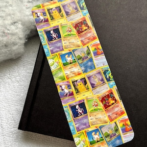 May include: A colourful bookmark featuring a collage of Pokemon trading cards. The cards feature various Pokemon characters, including Pikachu, Charizard, and Bulbasaur.