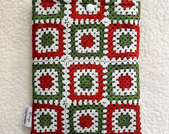 Peut inclure: Une housse de tablette en crochet rouge, verte et blanche avec une fermeture à bouton blanc. La housse porte une étiquette indiquant "Always September".