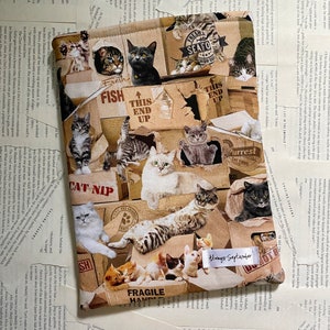 May include: A brown and beige fabric book cover featuring a collage of cats in cardboard boxes. The boxes have various labels, including "Fresh Seafood", "This End Up", "Cat Nip", "Purrest Cat Food", and "Fragile Handle". The text "Always September" is printed on a white ribbon.