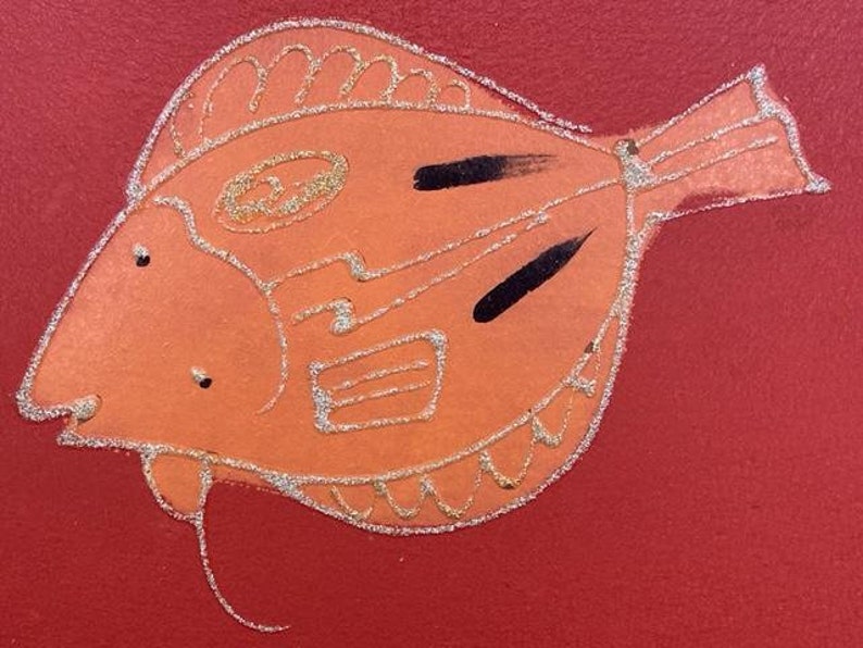 May include: A hand-painted orange fish with silver glitter details on a red background.