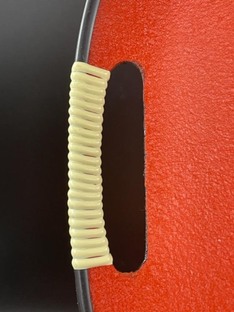 May include: A red tray with a black rim and a cream-colored rope handle.