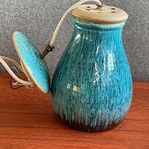 May include: A teal blue ceramic lamp with a round, teal blue shade. The lamp has a brown base and a white top.