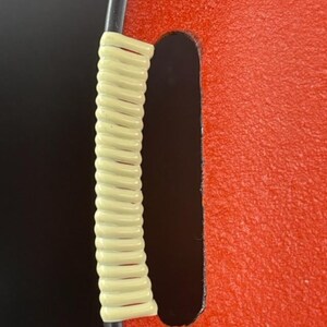 May include: A red tray with a black rim and a cream-colored rope handle.