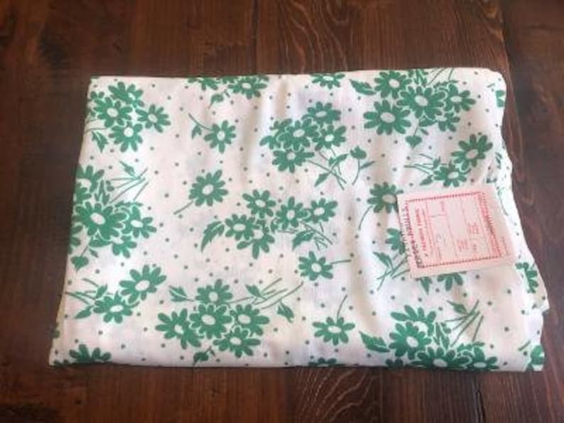 May include: White fabric with a green floral pattern. The fabric has small white dots and a label that reads "Premier Prints, Inc."