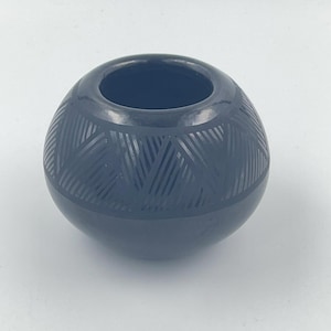 Puede incluir: Un cuenco de cerámica negro con un diseño geométrico. El cuenco es redondo y tiene un acabado liso y brillante.