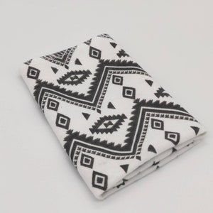 May include: White fabric with a black and white geometric pattern. The pattern features triangles, squares, and diamonds.
