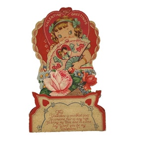 May include: Vintage Valentine's Day card featuring a girl holding a fan with a heart design. The card has a red and white heart border with the words "Valentine Greetings". The text on the card reads: "This Valentine is one that goes To someone fair as any rose To bring my love and in a line Say Won't you be my Valentine?"