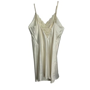 May include: A white satin slip with a lace trim. The slip has thin straps and a V-neckline.