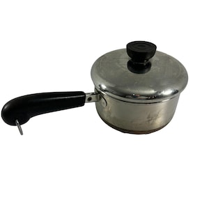 May include: A silver saucepan with a black handle and a black knob on the lid. The saucepan has a copper bottom.