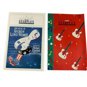 May include: Two program brochures for a performance of the music of Andrew Lloyd Webber at the Coca-Cola Starplex. The left brochure features a blue background with stars and a photo of a musical score. The right brochure features a red background with a cityscape and musical notes. The text on the left brochure reads "The Music of Andrew Lloyd Webber" and "Special guest star Michael Crawford". The text on the right brochure reads "Coca-Cola Starplex".