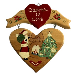 May include: Wooden Christmas sign with a red heart that says "Christmas is Love". The sign is decorated with a painted scene of Santa Claus and a Christmas tree.