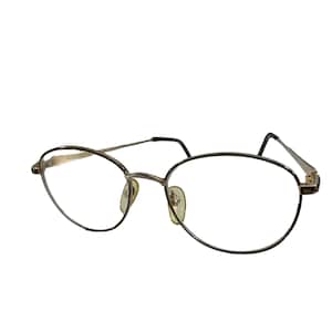 May include: Gold-tone metal eyeglasses with oval-shaped lenses and thin frames.