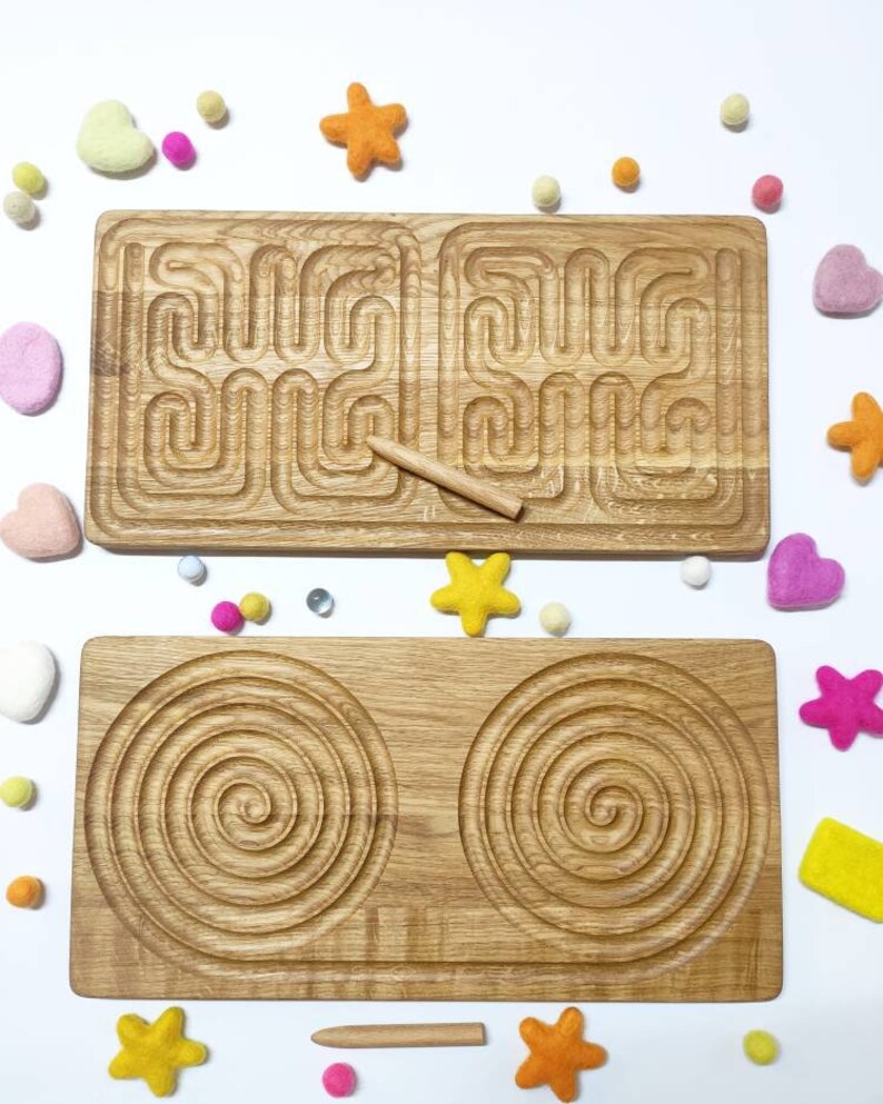 May include: Two wooden tracing boards for children. The top board has a maze pattern and the bottom board has two spiral patterns. Both boards are made of natural wood and come with a wooden stylus.