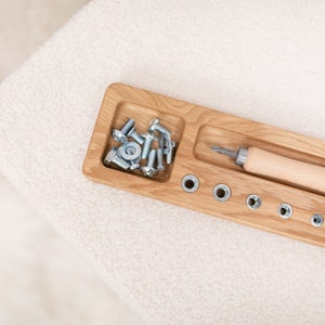 May include: A wooden tray with a compartment for screws and nuts, a screwdriver with a wooden handle, and a row of holes for matching the screws and nuts.
