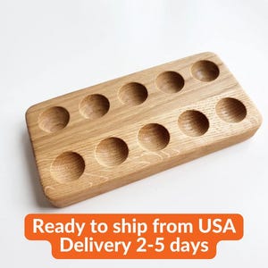 May include: A rectangular wooden egg holder with ten circular indentations. The holder is made of light-colored wood and has a smooth, finished surface. The text "Ready to ship from USA Delivery 2-5 days" is at the bottom.