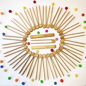 Puede incluir: Un conjunto de 20 pinzas de madera dispuestas en c&iacute;rculo sobre un fondo blanco. Las pinzas son de color madera natural y tienen un mango redondeado. Las pinzas est&aacute;n etiquetadas como "Skylar" y "Rowan".